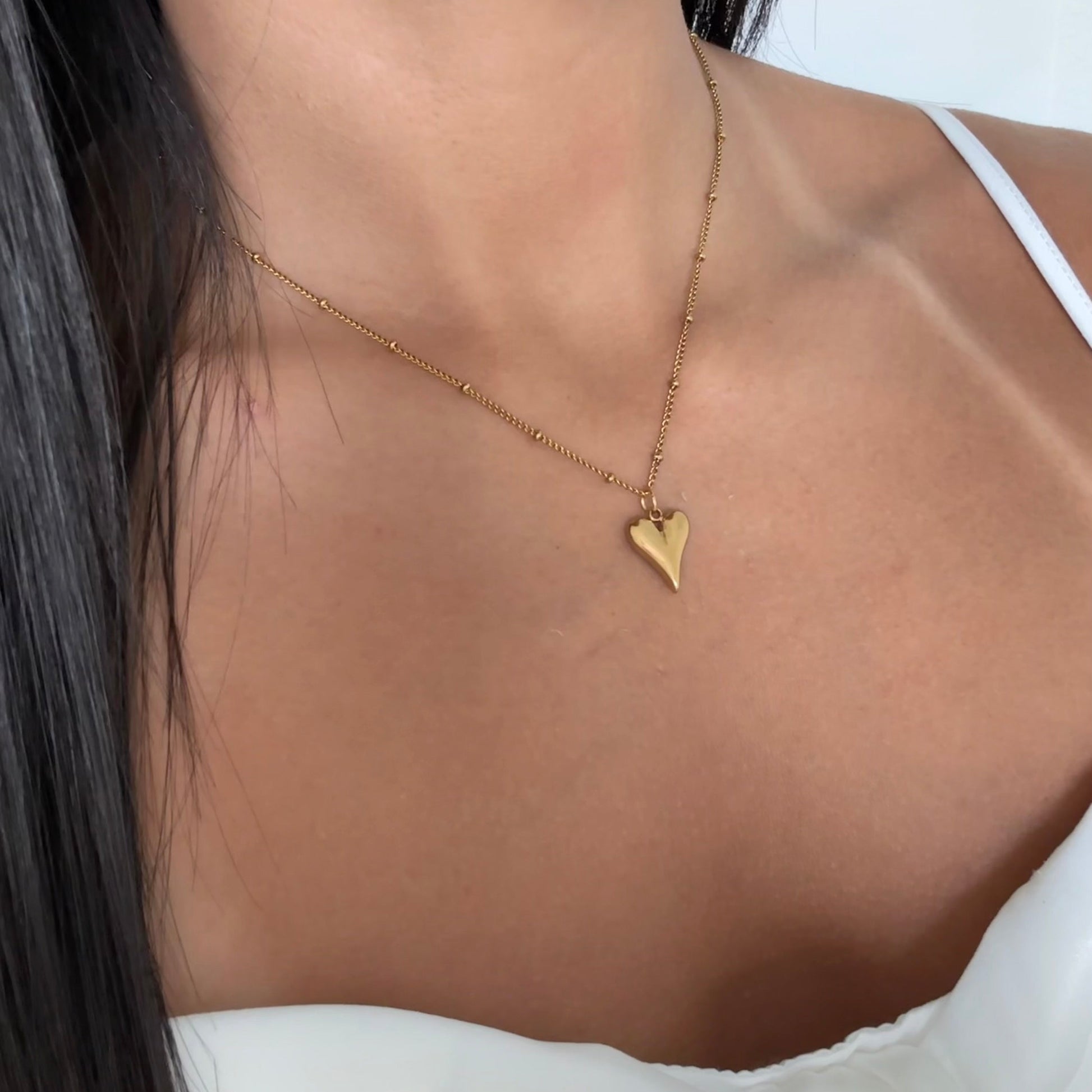 Close-up of bold gold heart pendant – Amora necklace, chic and romantic

